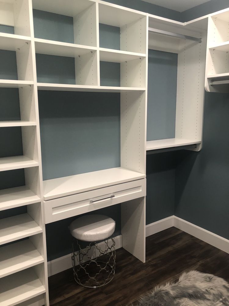 A walk in closet with lots of shelves and a desk.