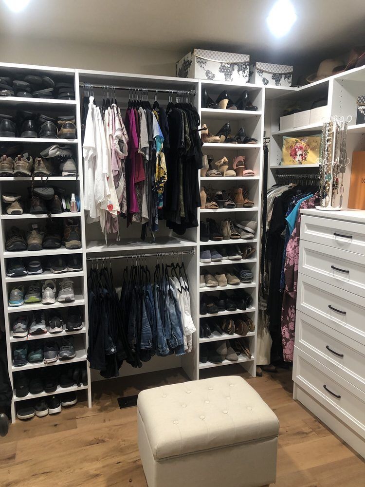 A walk in closet filled with lots of clothes and shoes.