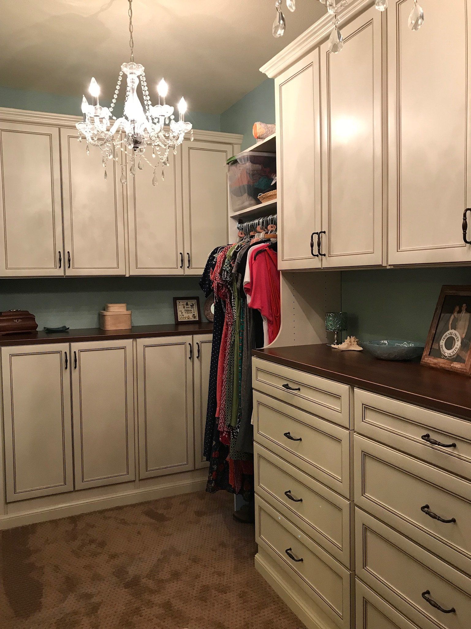 A walk in closet with white cabinets and drawers