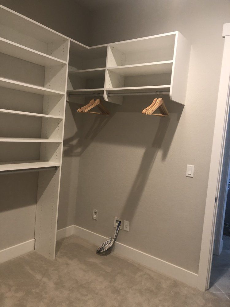 A walk in closet with white shelves and wooden hangers.