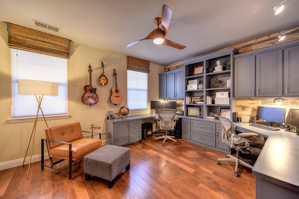 A home office with a ceiling fan and guitars hanging on the wall.
