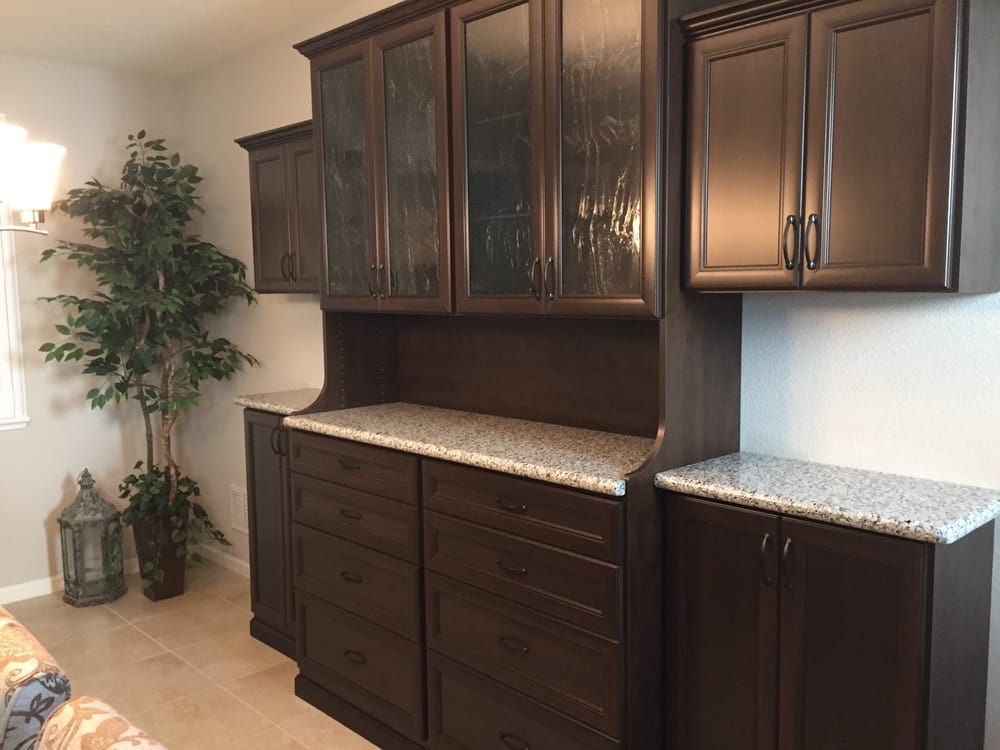 A living room with dark wood cabinets and granite counter tops.