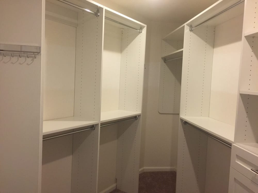 A walk in closet with lots of shelves and hooks