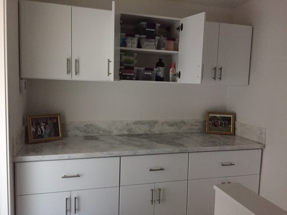A kitchen with white cabinets and marble counter tops