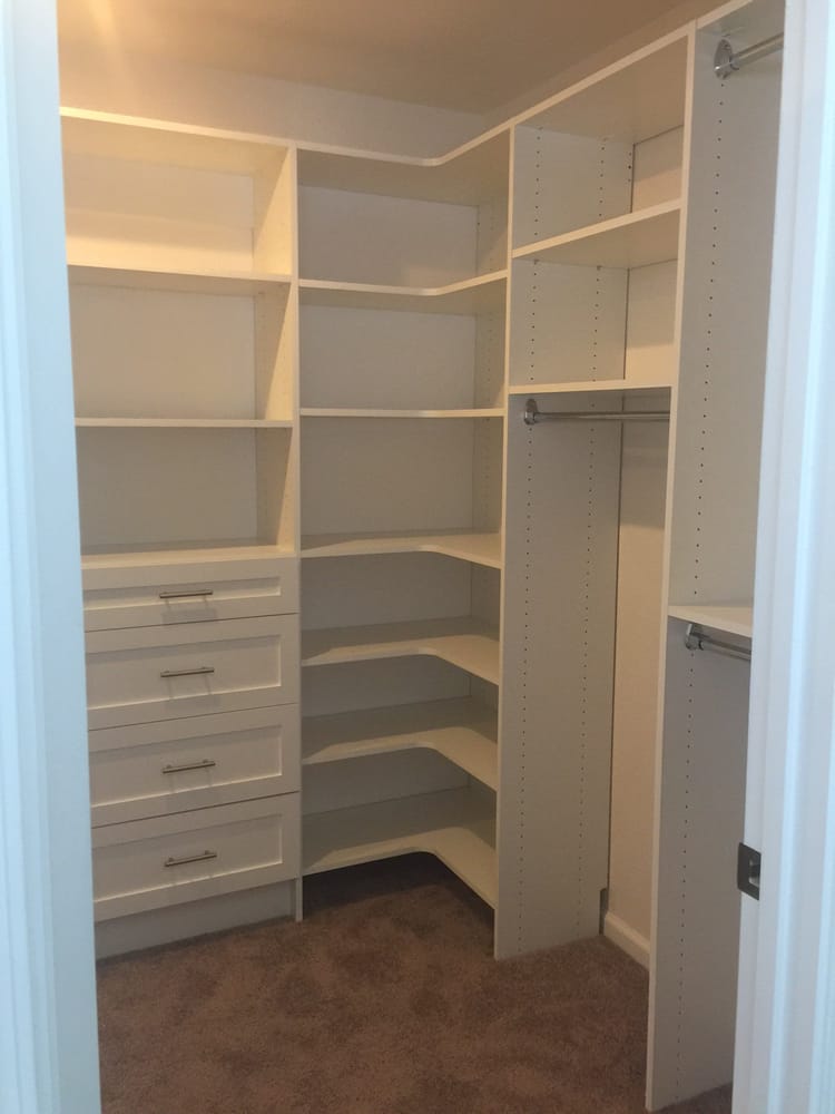 A walk in closet with lots of shelves and drawers