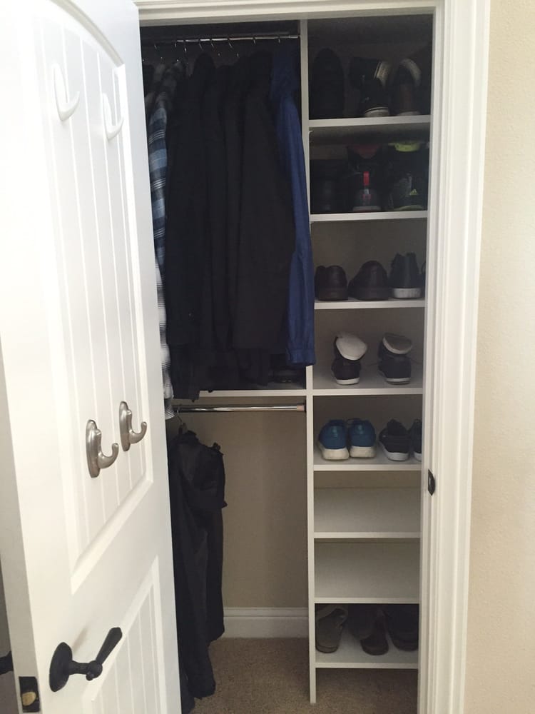A closet filled with clothes and shoes with the door open
