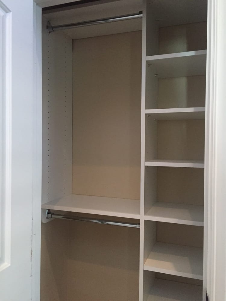 An empty closet with shelves and a hanging rail.