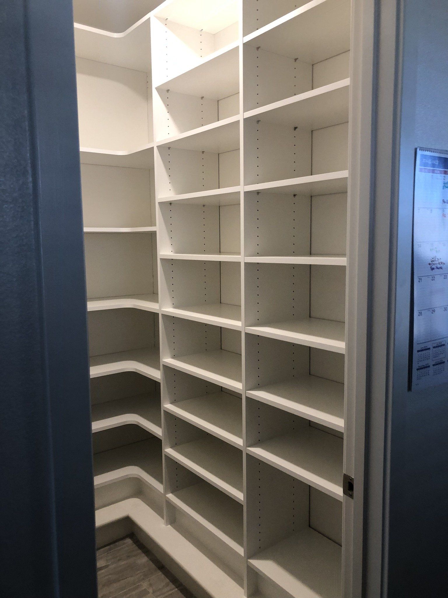 A walk in closet with lots of shelves and a door.