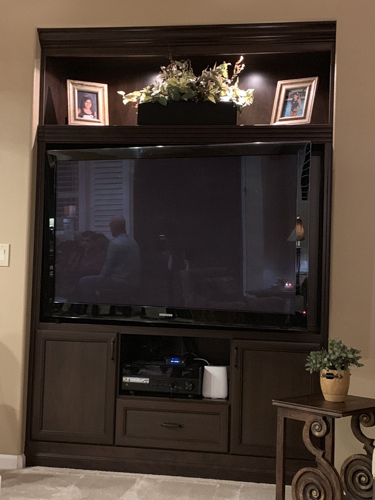 A large flat screen tv is sitting on top of a wooden entertainment center