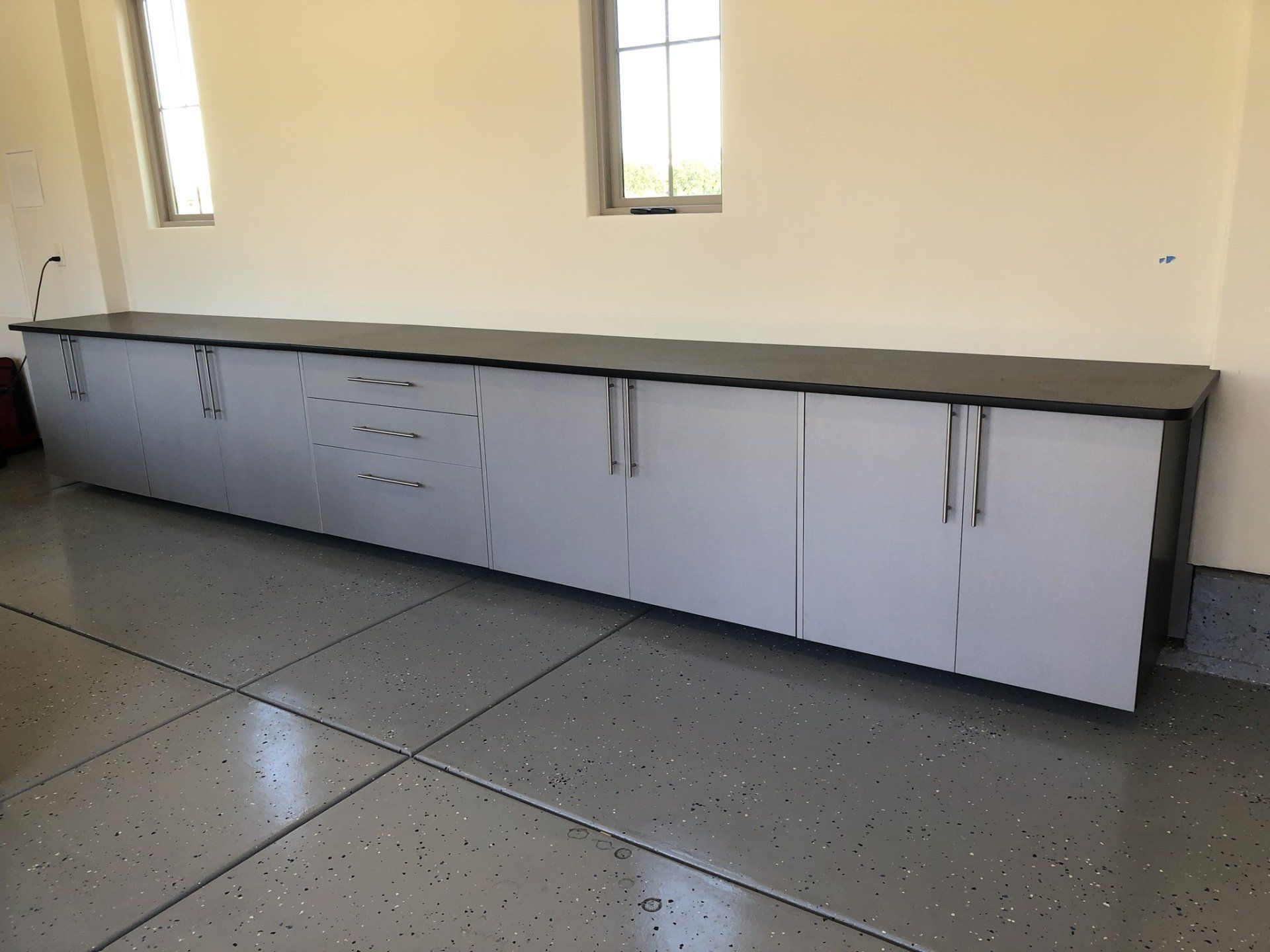 A long cabinet in a garage with a window in the background