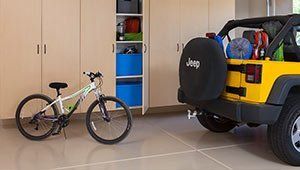 A jeep is parked in a garage next to a bicycle.