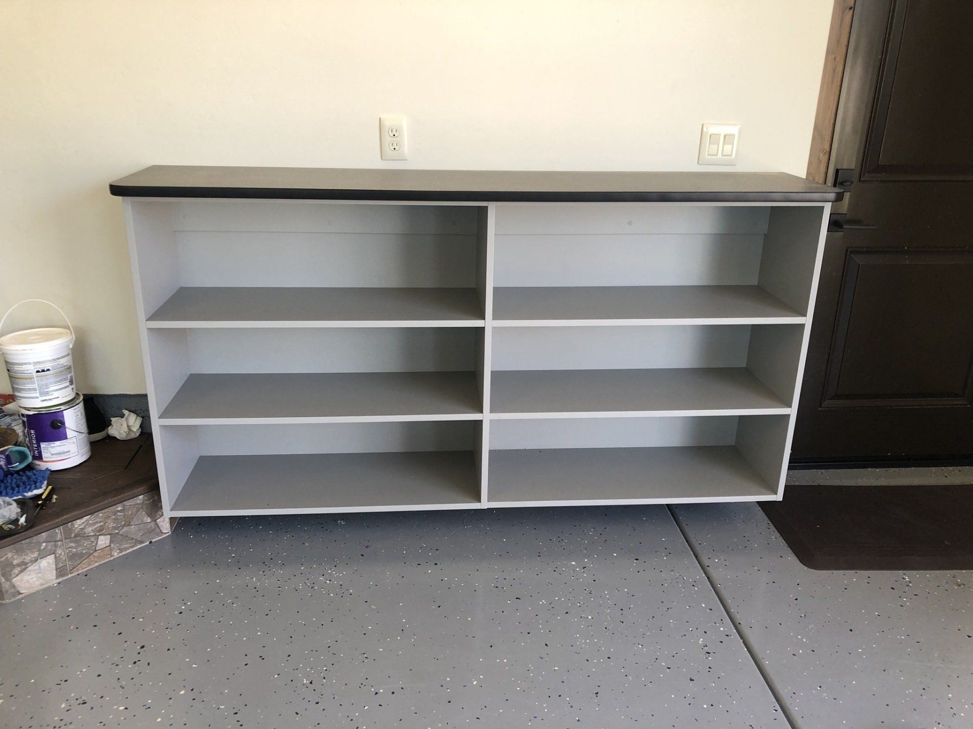 An empty shelf in a garage next to a door.