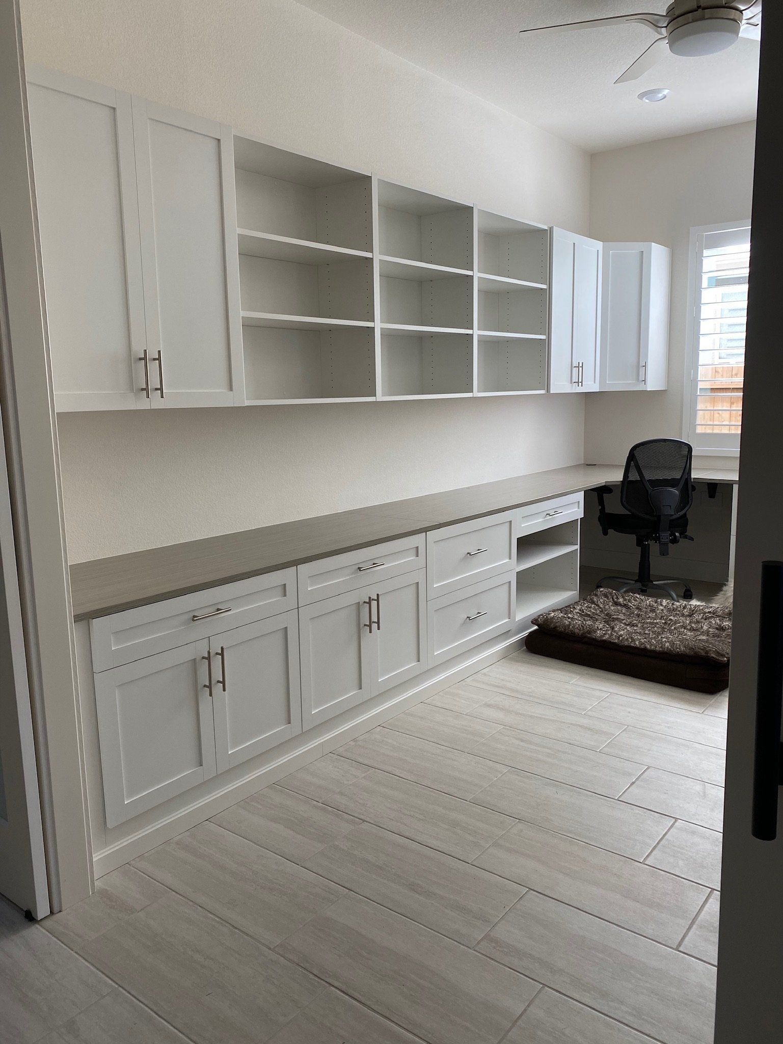 A room with white cabinets and a ceiling fan