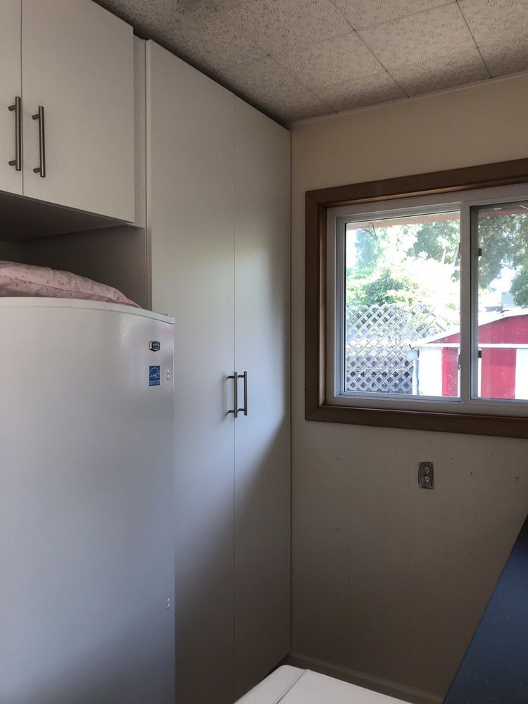A laundry room with white cabinets and a window