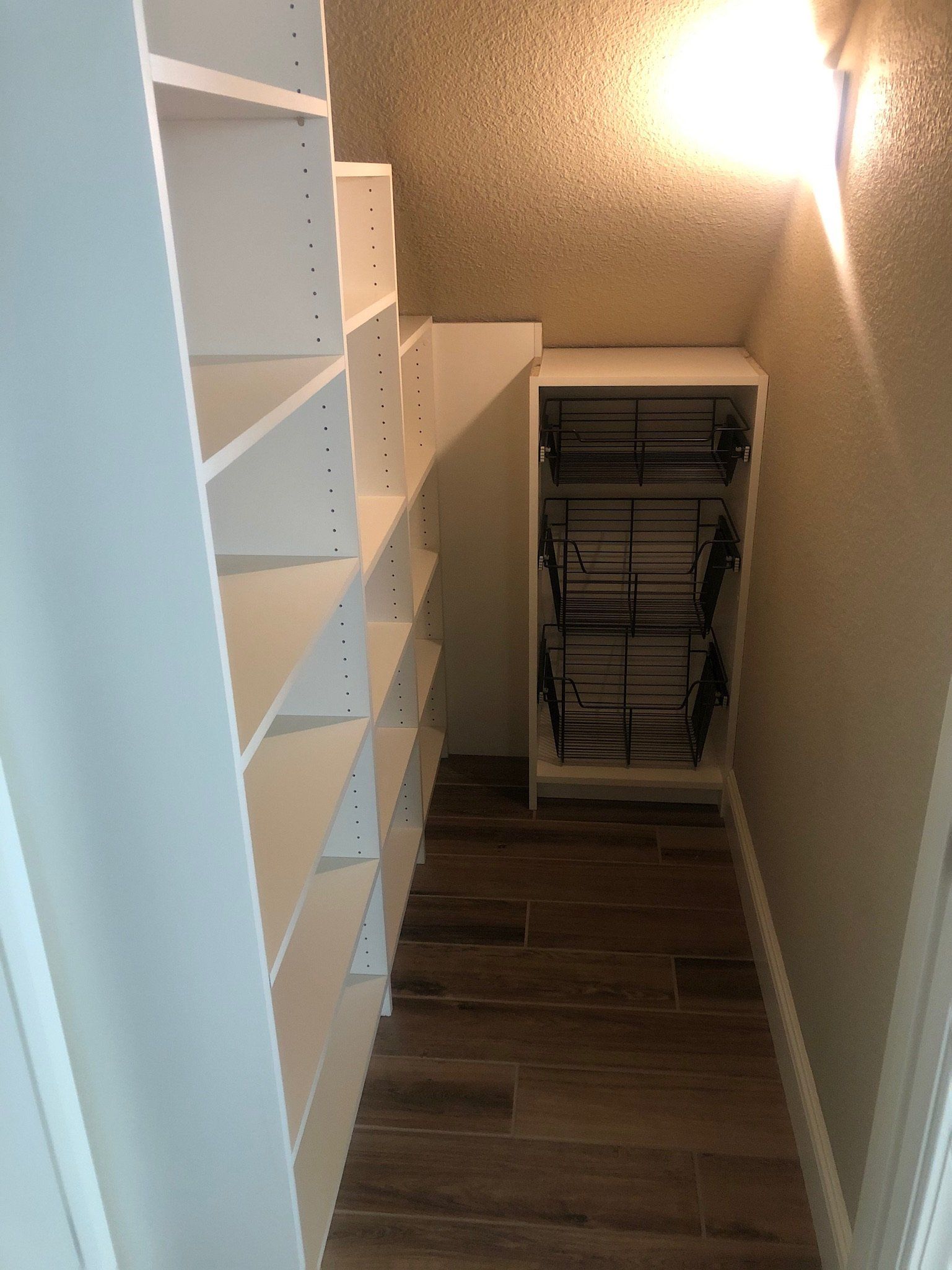 A small closet with white shelves and a shoe rack.