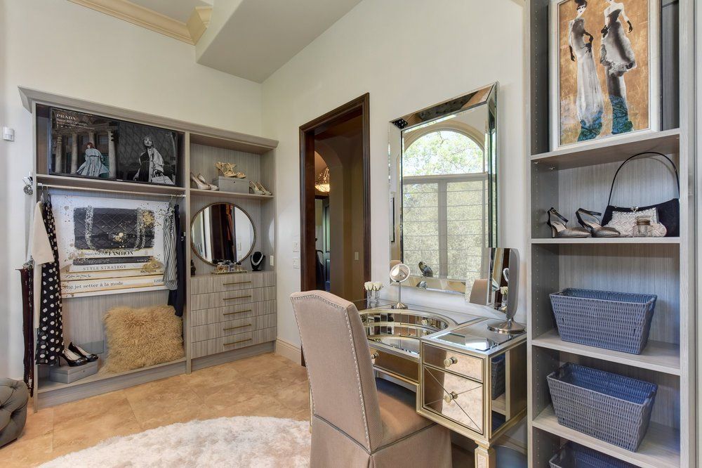 A walk in closet with a vanity and a mirror.