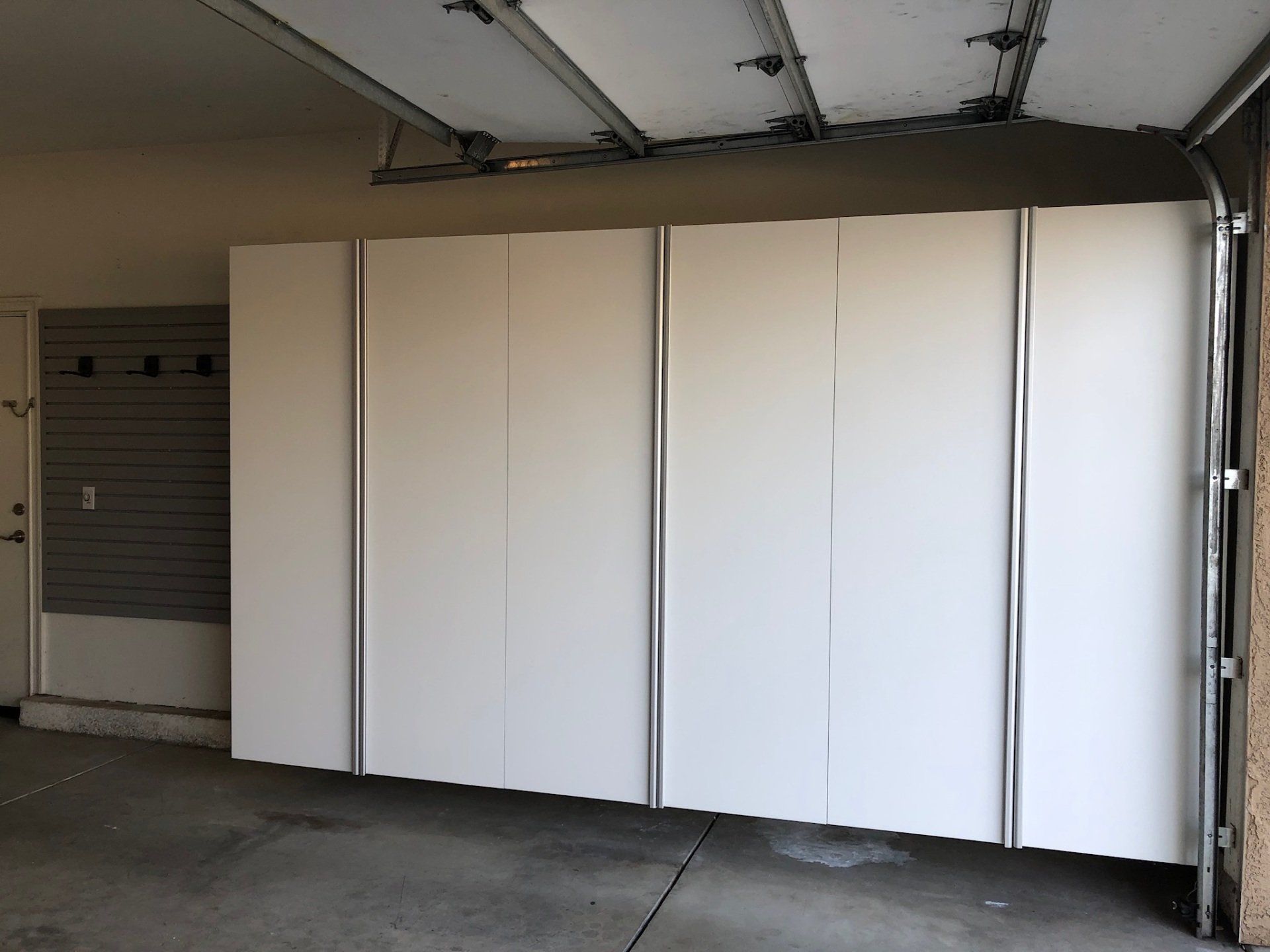 A garage with white cabinets and a garage door open