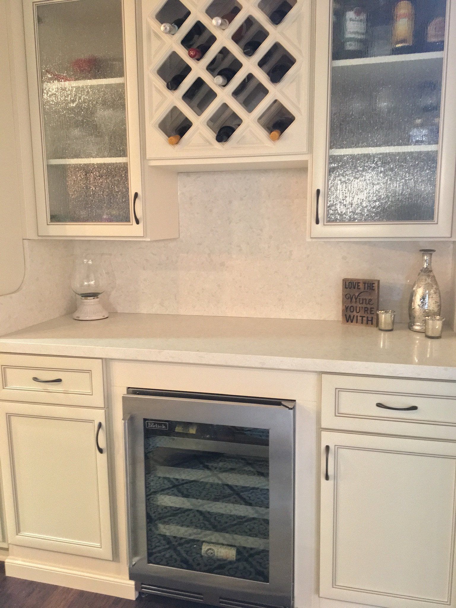 A kitchen with white cabinets and a wine cooler