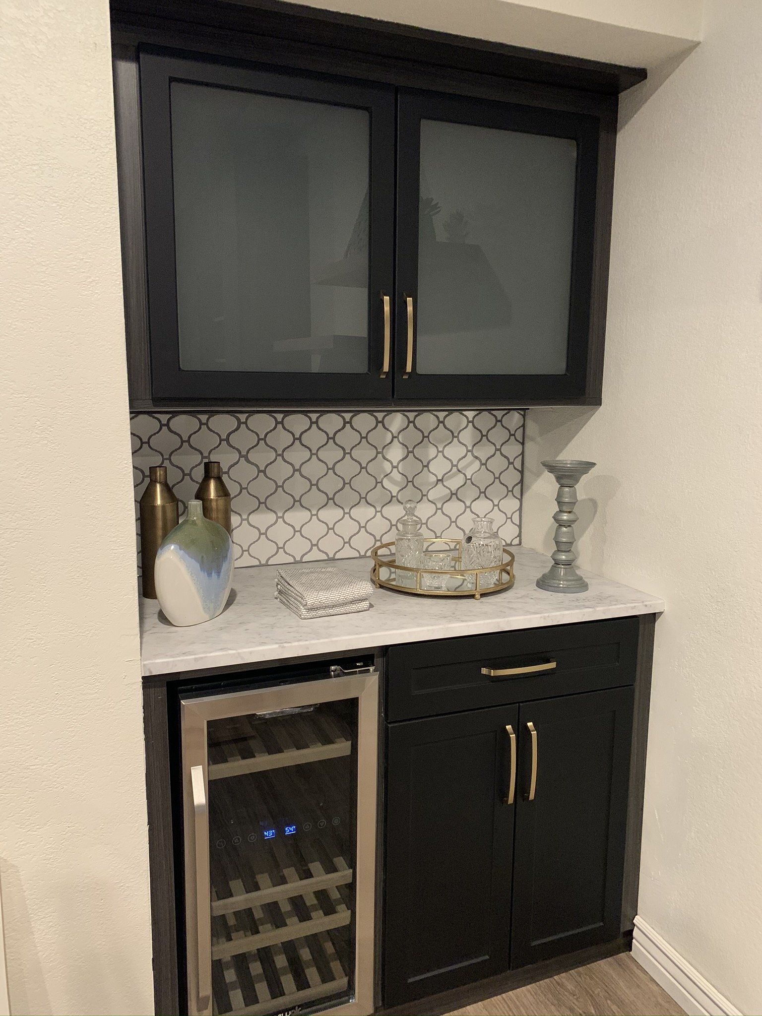 A kitchen with black cabinets and a wine cooler.