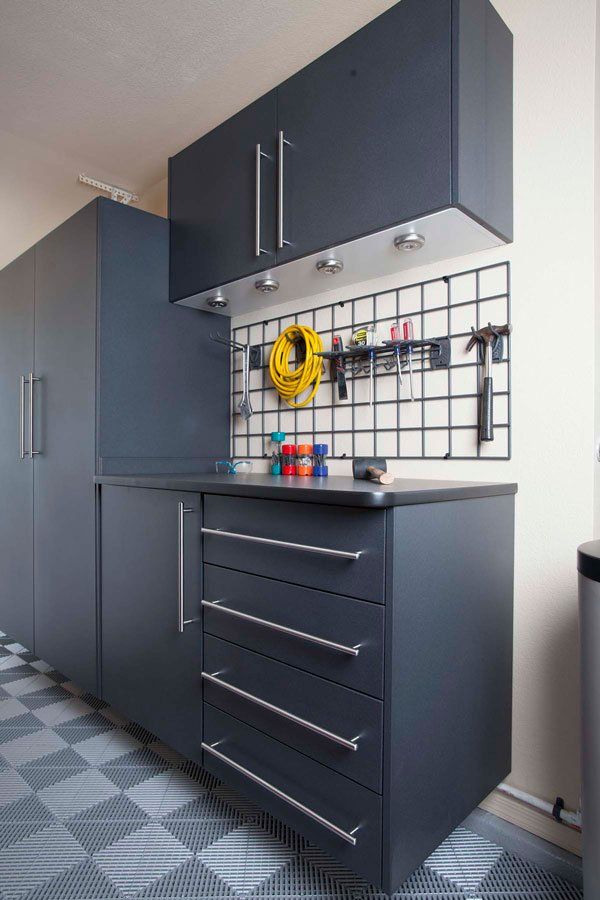 A garage with lots of cabinets and drawers and a stainless steel counter top.
