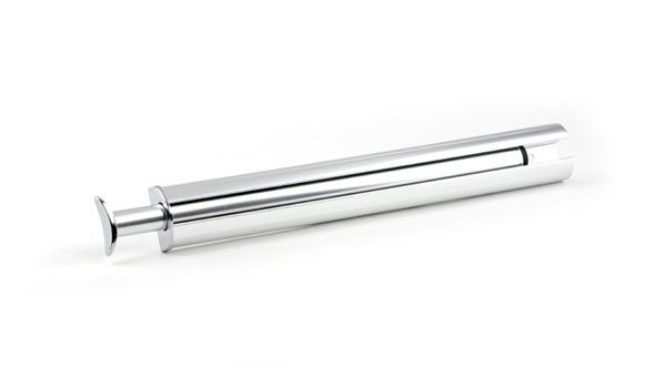 A metal syringe is sitting on a white surface.