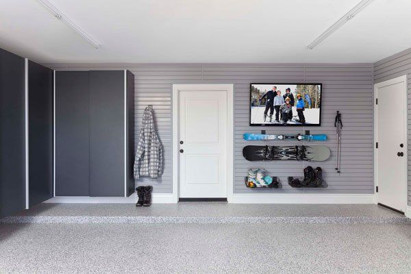 A garage with a tv on the wall and snowboards hanging on the wall.