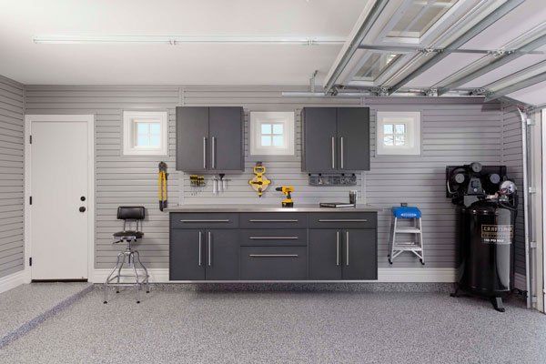 A garage with gray cabinets , a sink , and a ladder.