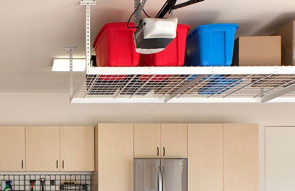 A garage with a ceiling rack filled with boxes and a garage door opener.