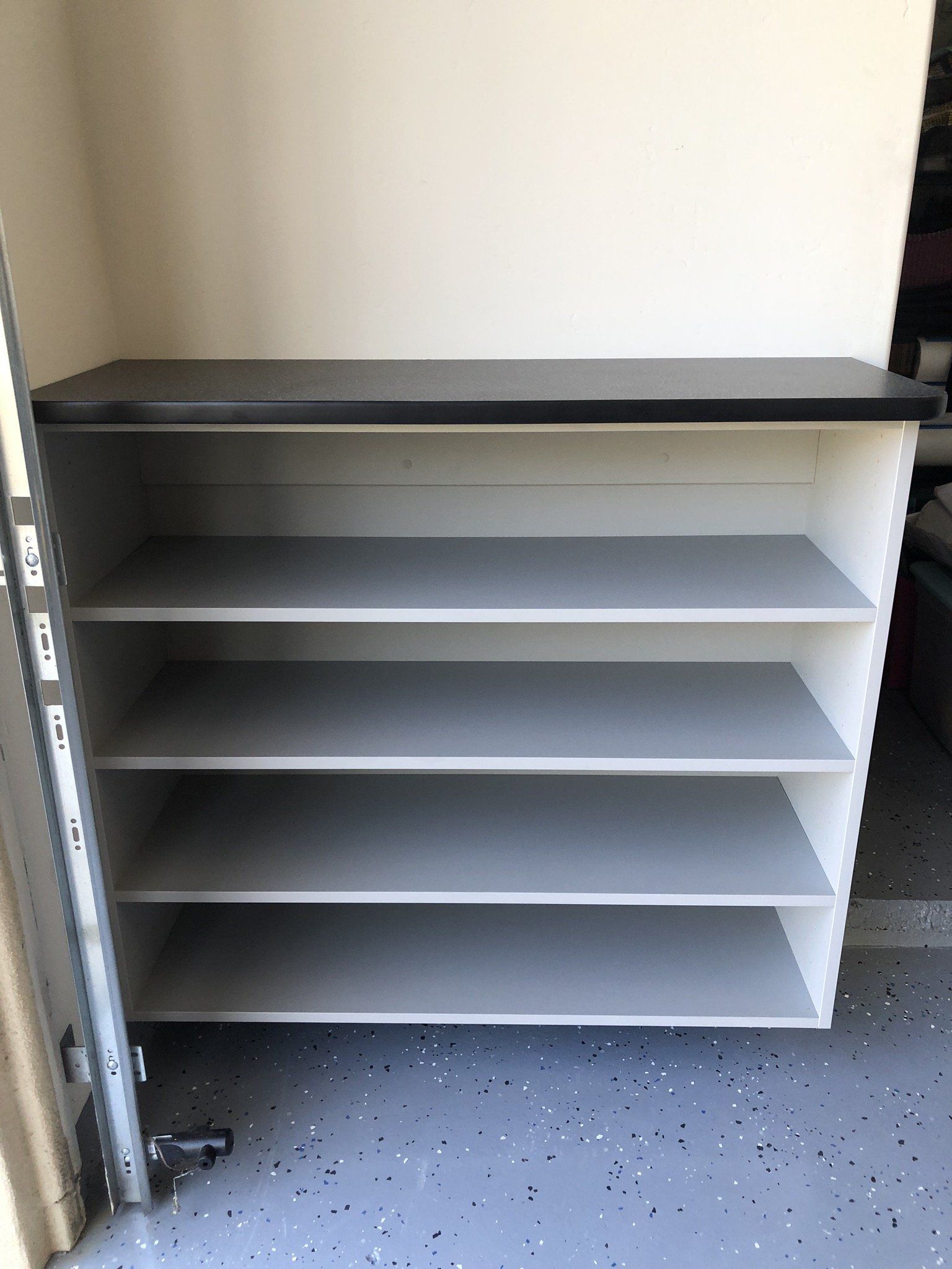 A shelf with four shelves and a shelf above it in a garage.