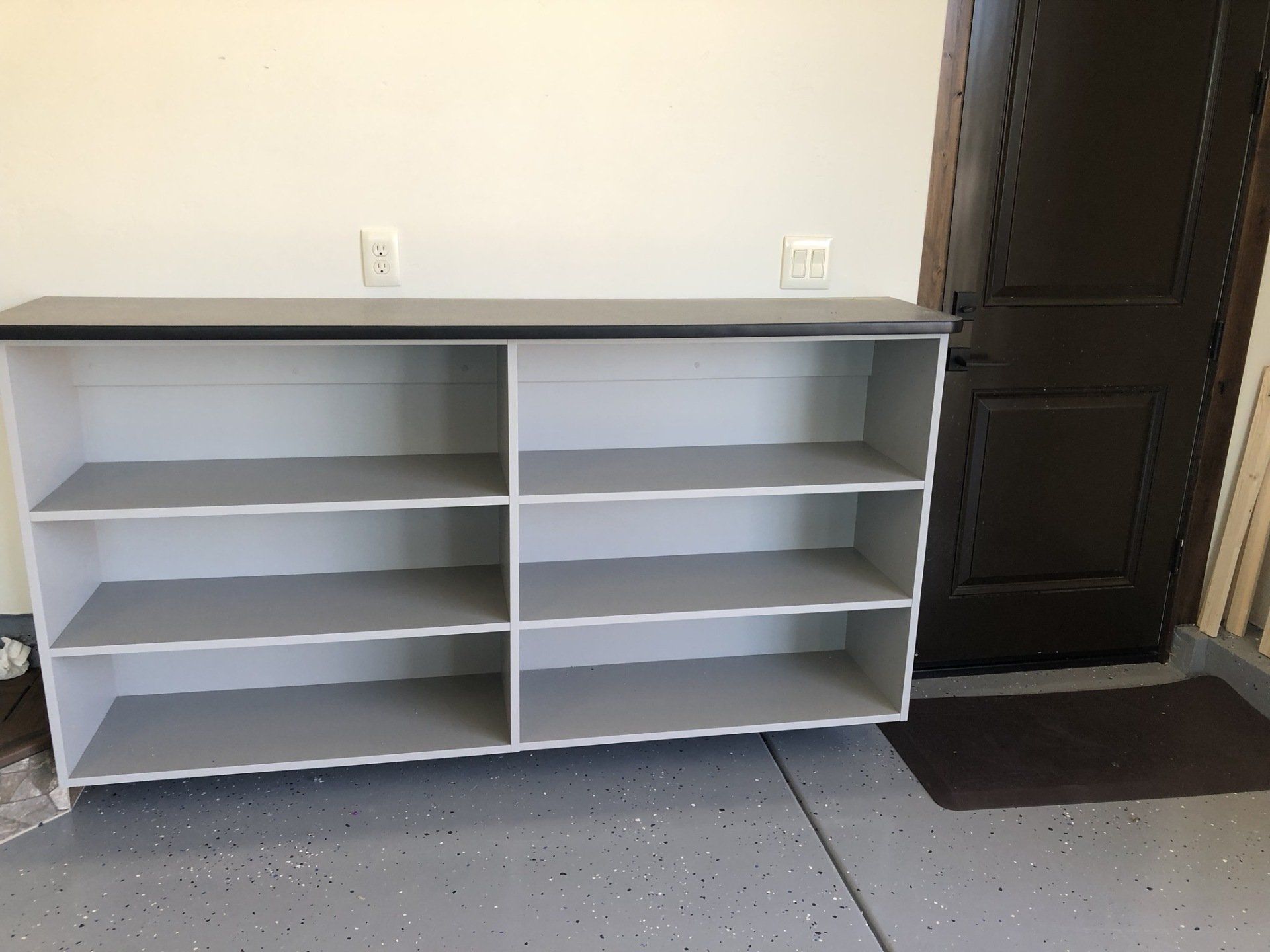 An empty shelf is sitting in a garage next to a door.