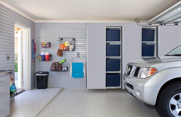 A silver suv is parked in a garage with lots of storage space.