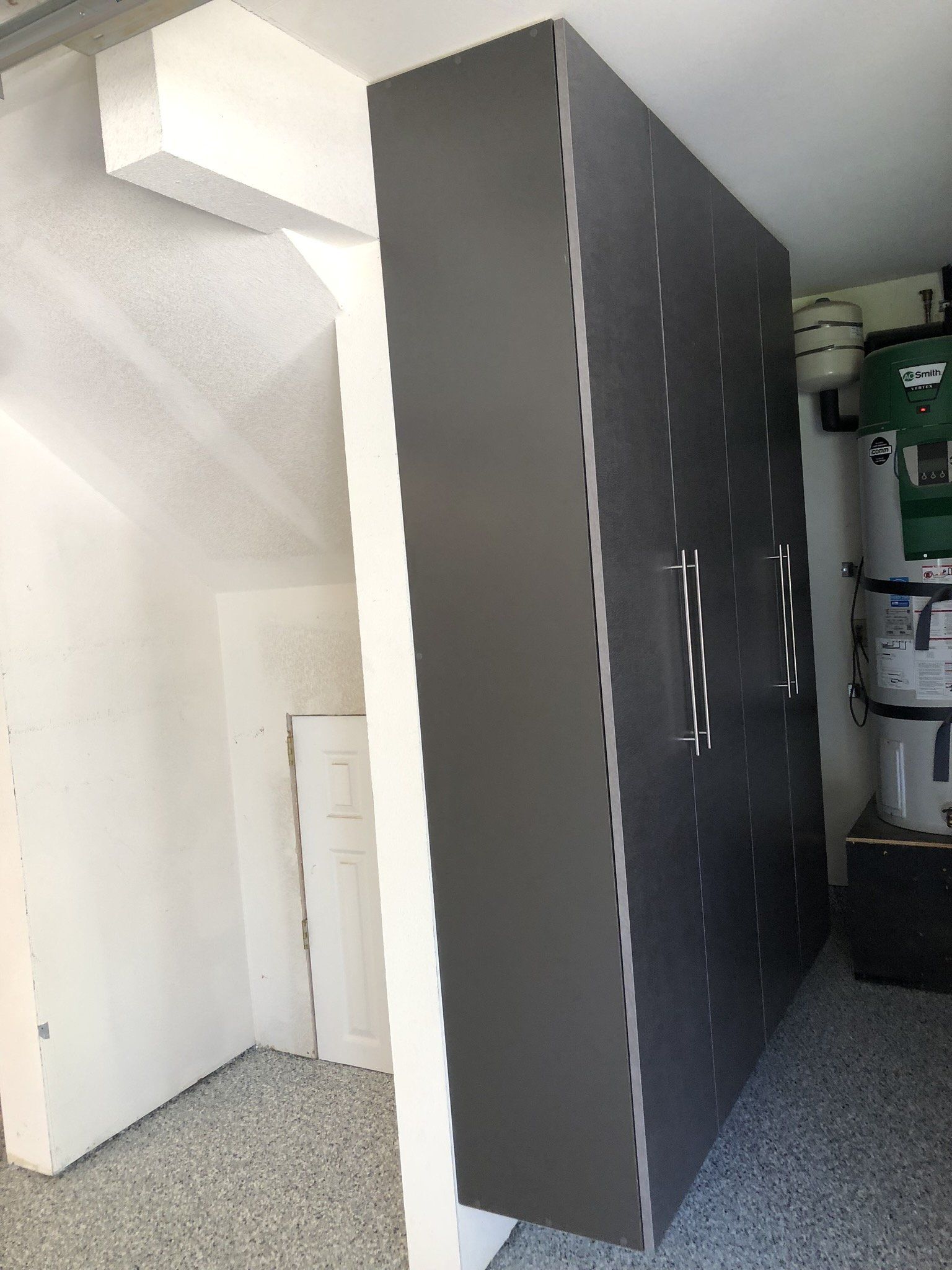 A large gray cabinet in a garage next to a staircase.