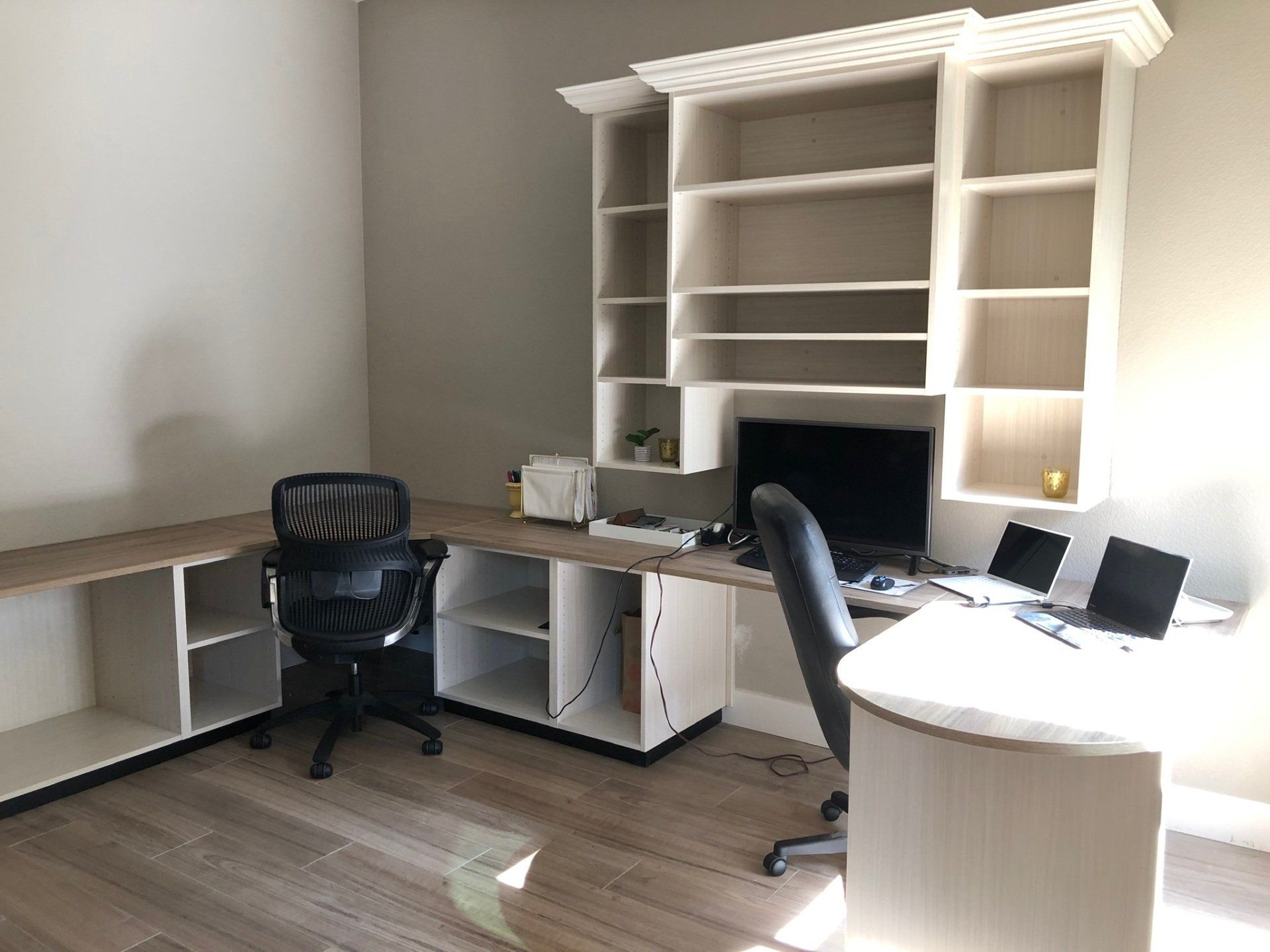 A room with a desk , chair , computer and shelves.