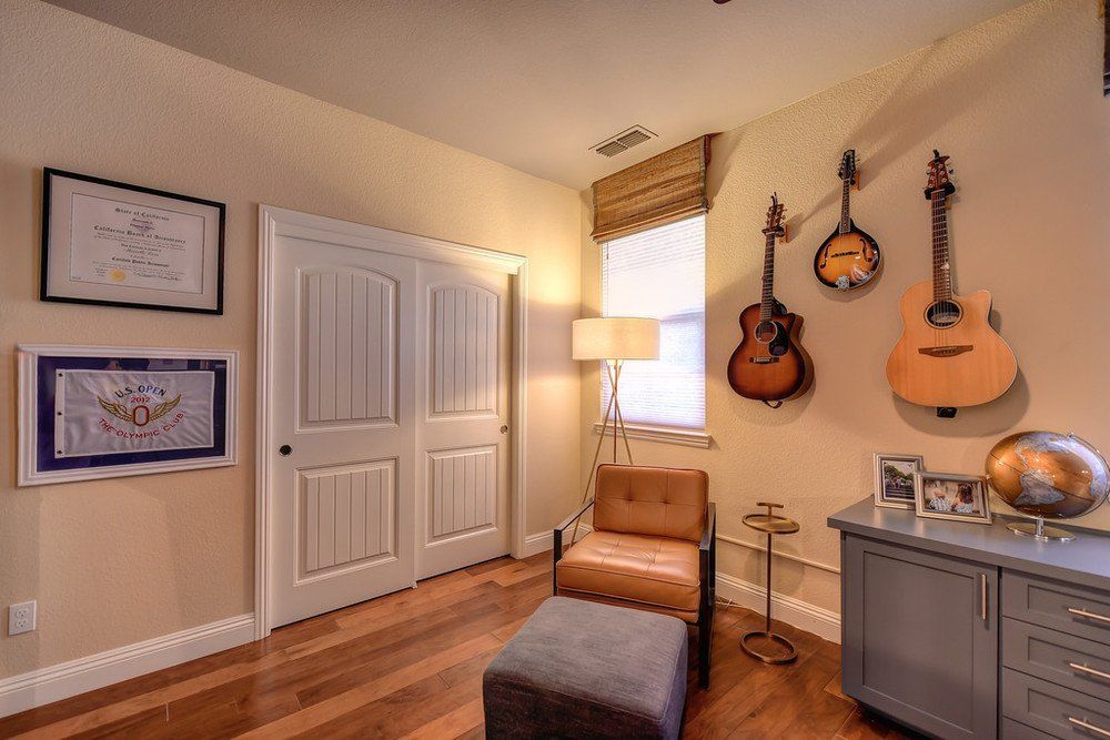 A room with guitars hanging on the wall and a chair.
