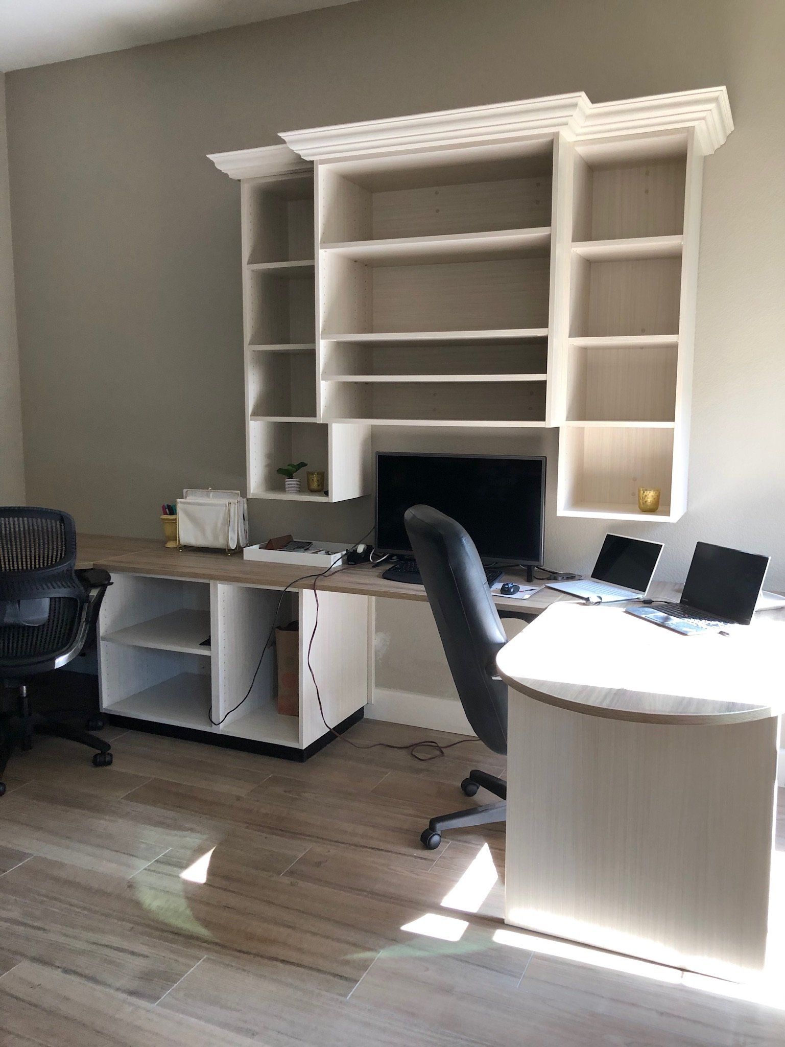A room with a desk , chair , computer and shelves.