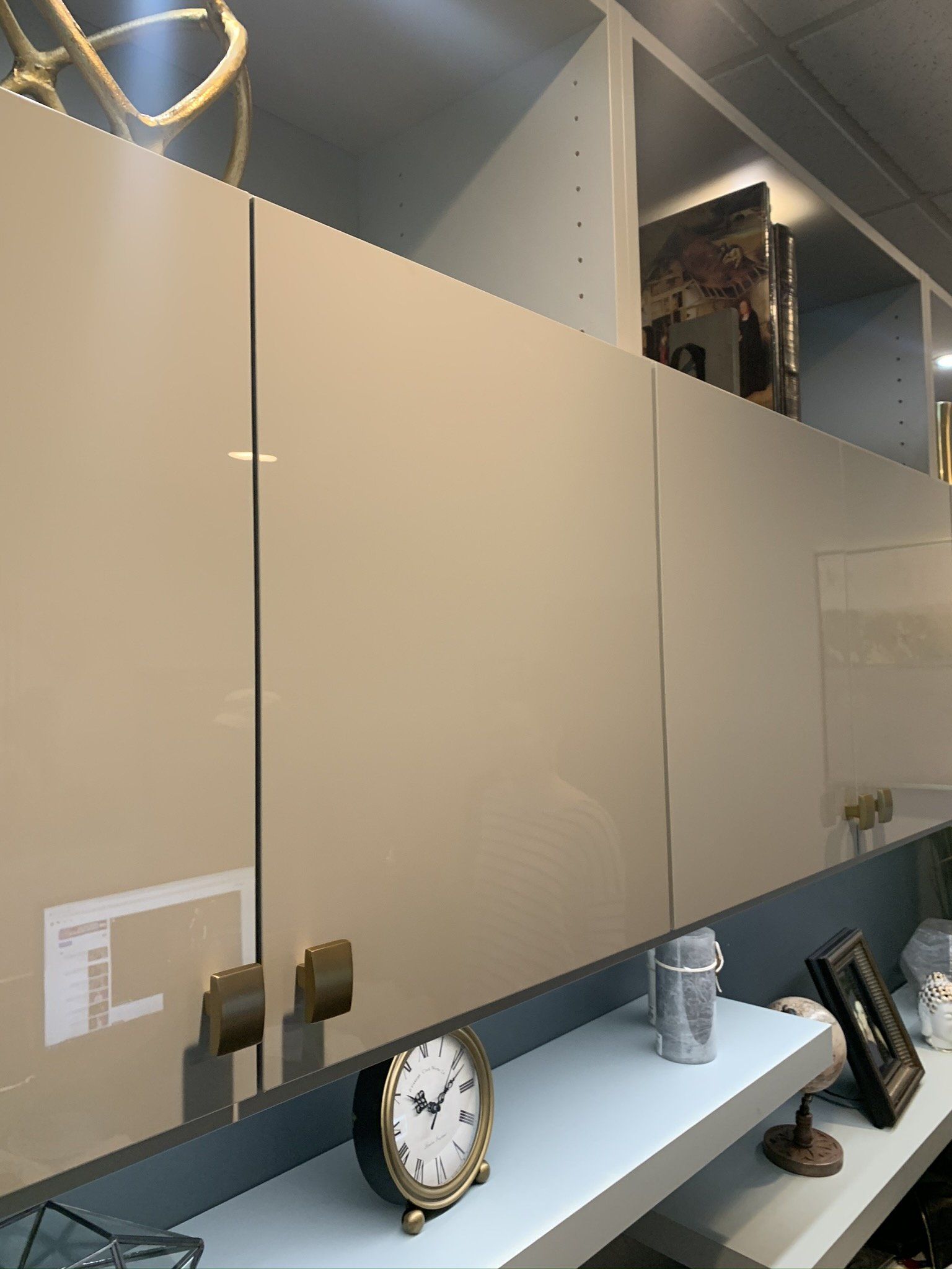 A clock is sitting on a shelf next to a cabinet.