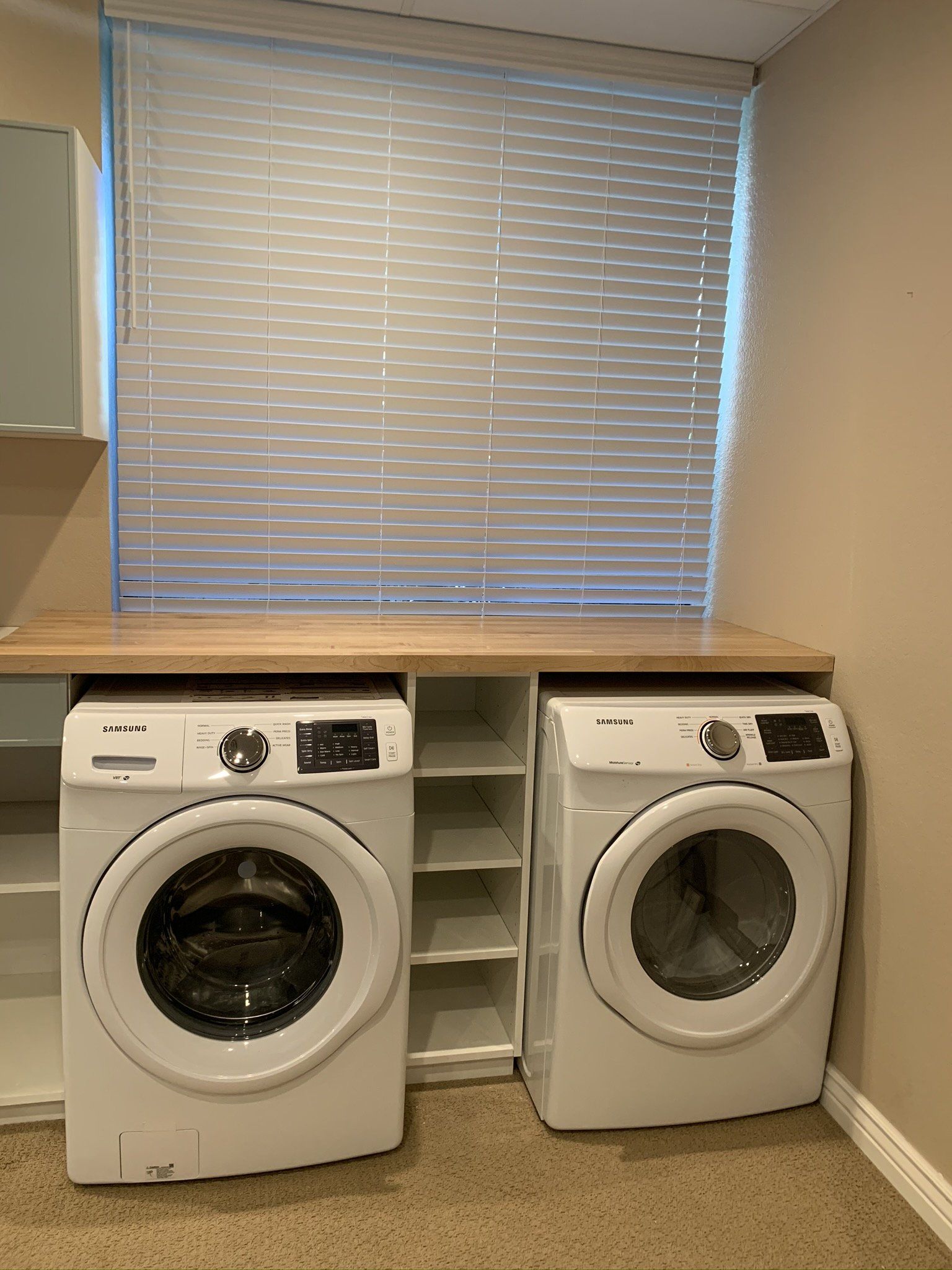 A laundry room with two washing machines and a window.
