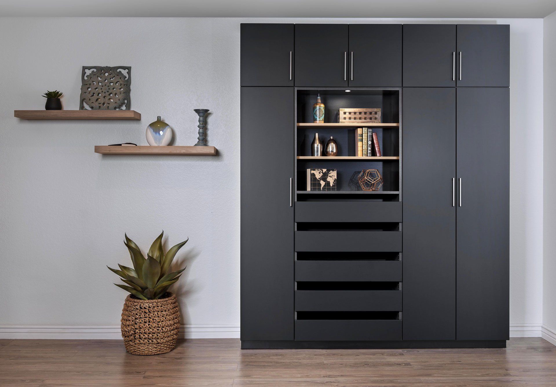 A room with black cabinets and shelves and a potted plant