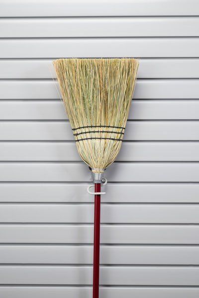 A broom is hanging on a hook on a wall.