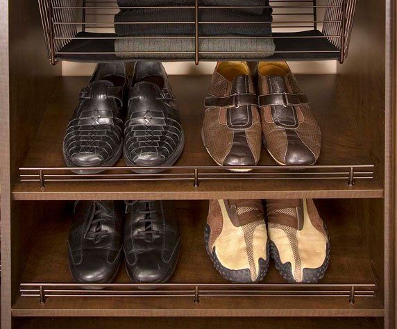 Three pairs of shoes are lined up on a shelf in a closet.
