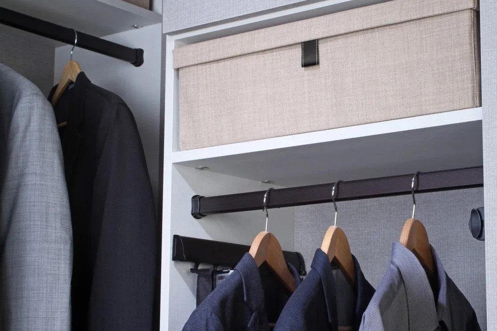 A closet filled with clothes and a box on the shelf.