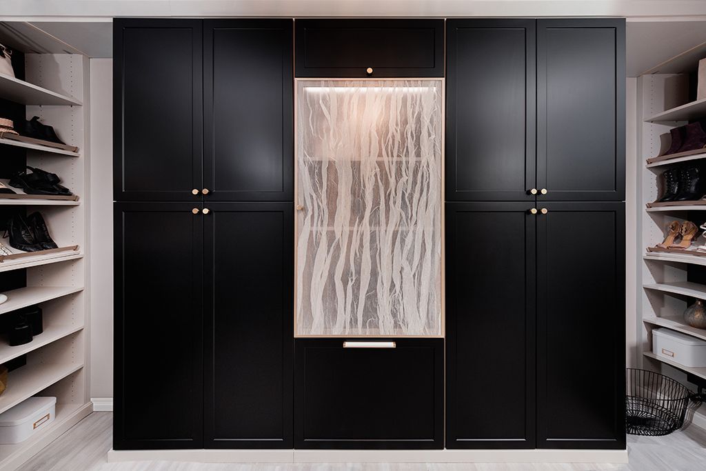 A walk in closet with black cabinets and white shelves.