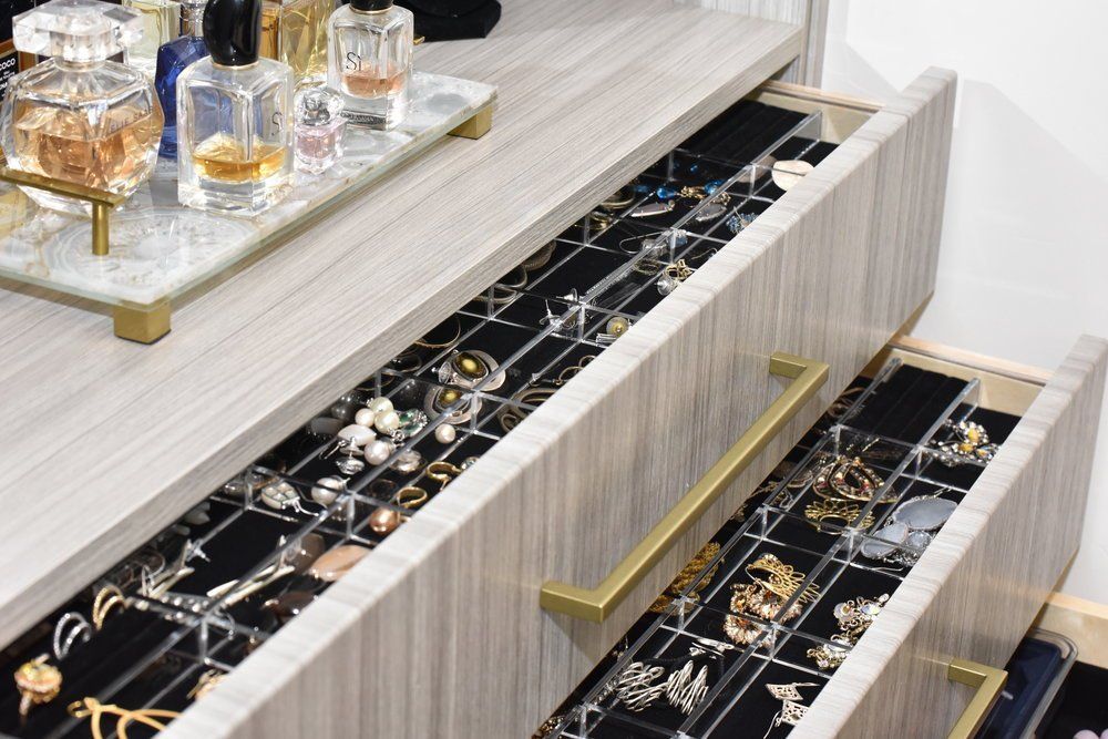 A dresser with two drawers filled with jewelry and perfume.
