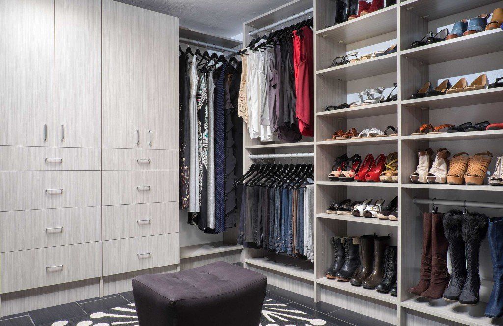 A walk in closet filled with lots of clothes and shoes.