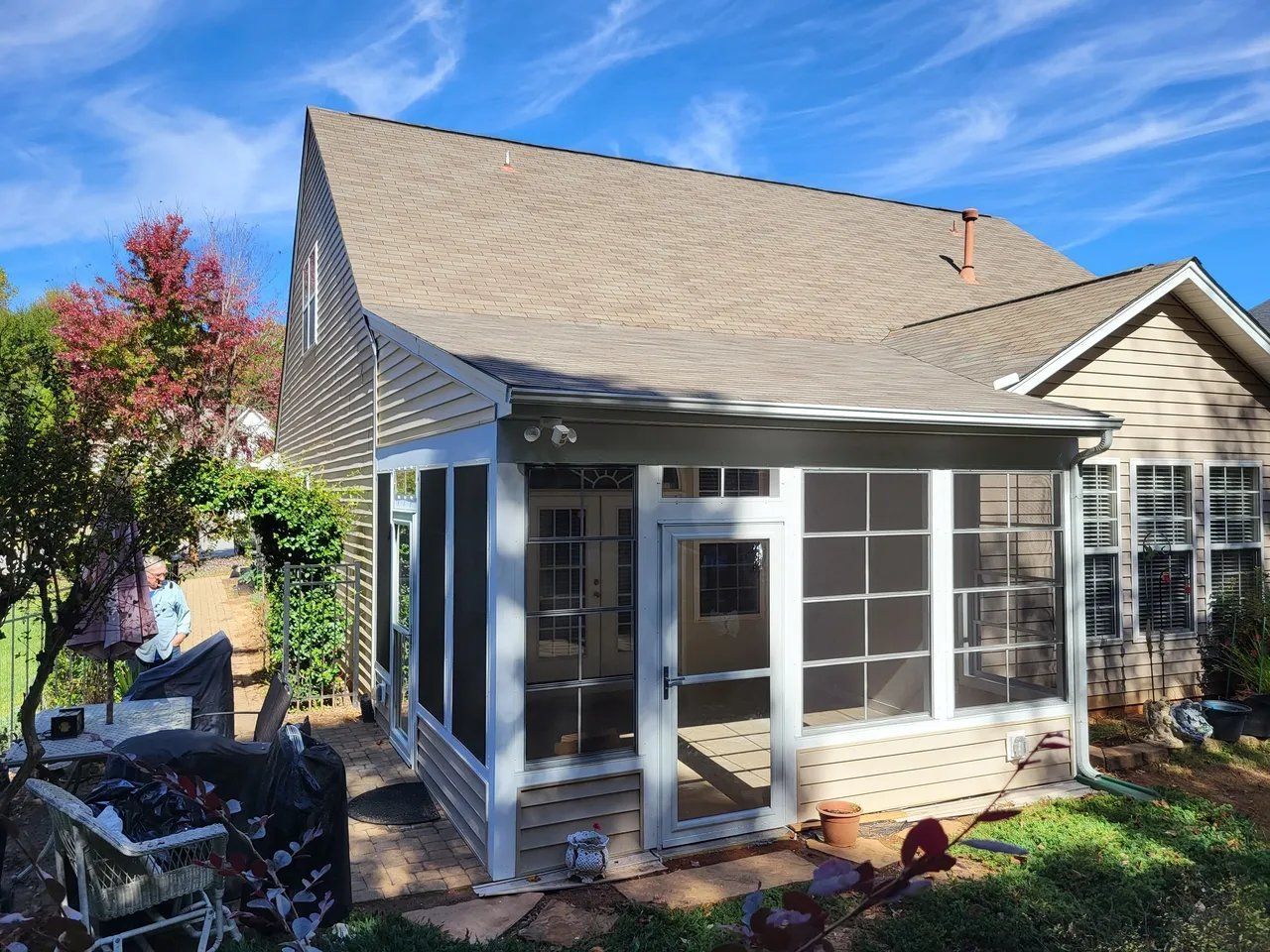A screened in porch in the backyard of a house