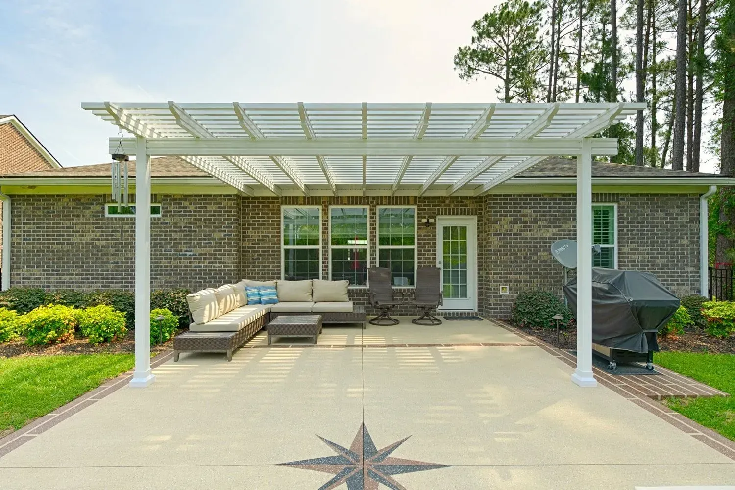Back patio with white pergola, outdoor seating, grill, and paver patio in front of a brick house