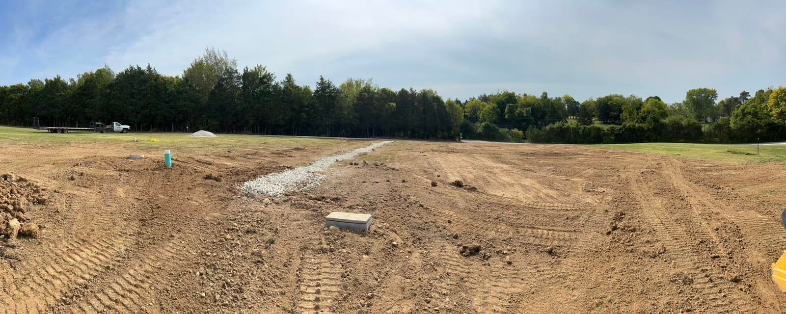 Woman in straw hat smiles, holding wine glass near a lake.