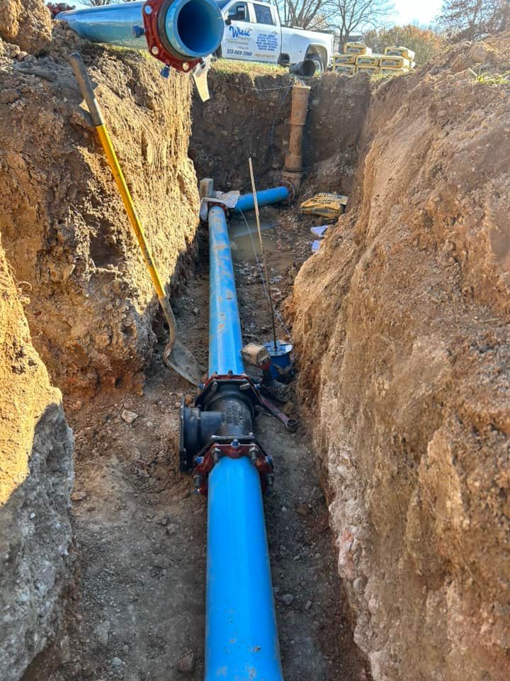 Woman in straw hat smiles, holding wine glass near a lake.