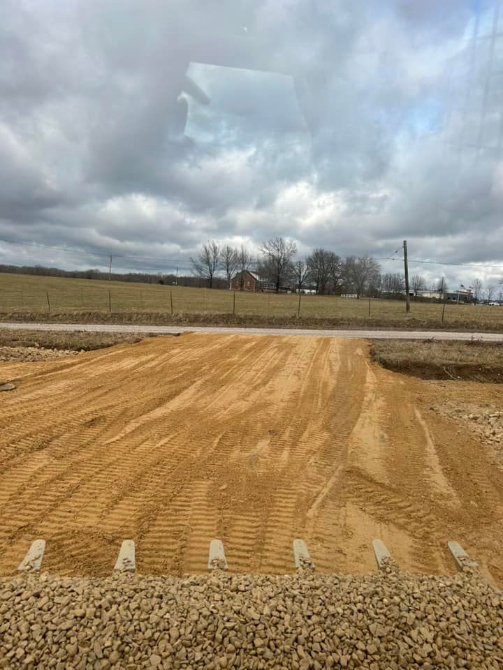 Woman in straw hat smiles, holding wine glass near a lake.