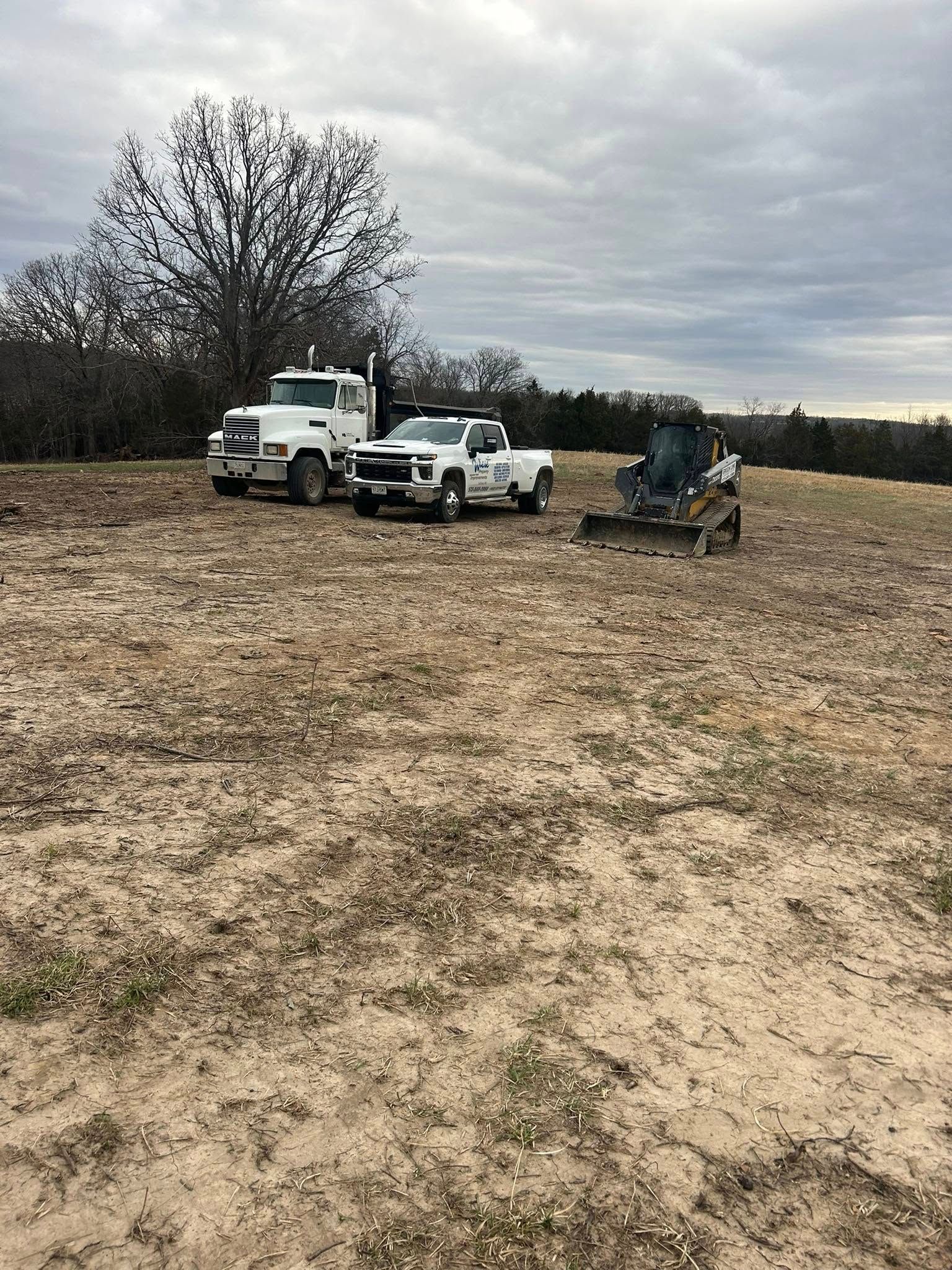 Woman in straw hat smiles, holding wine glass near a lake.